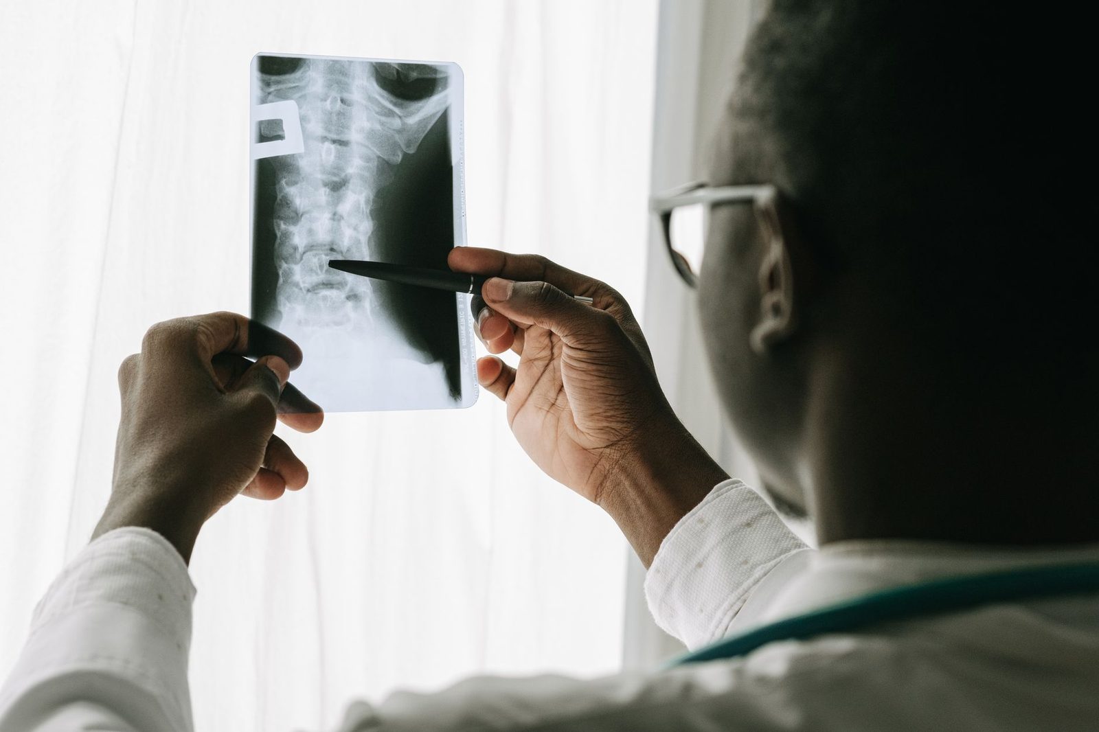 A doctor points a pen at a spine X-ray film during an examination in a hospital.