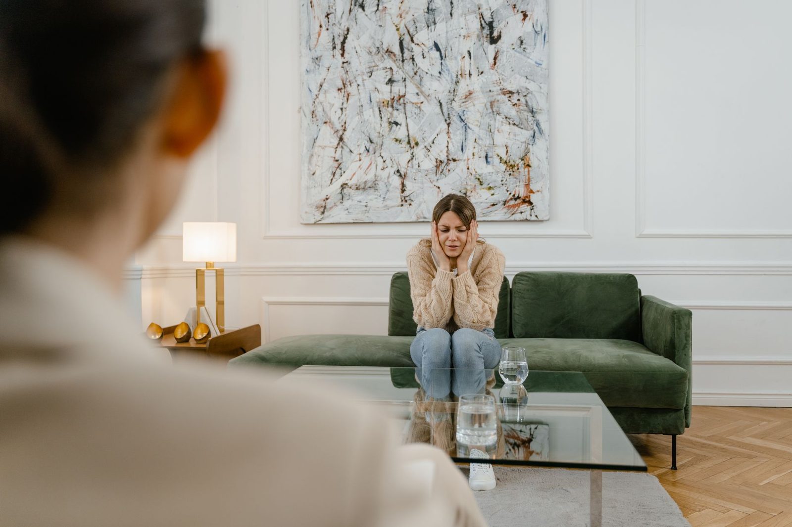 A woman sits looking distressed and thoughtful during an indoor counseling session.