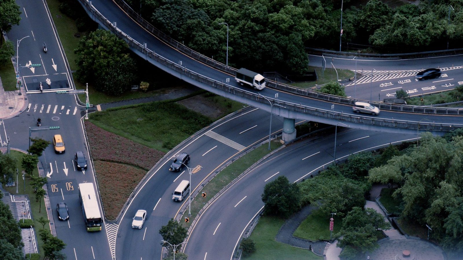 Aerial view of a busy multi-level urban intersection with cars moving along crisscrossing roads.