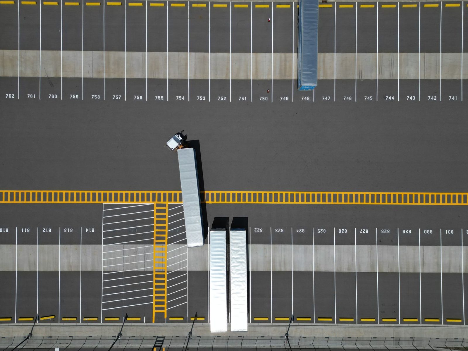 Aerial view of a large parking lot with marked spaces and several semi-trucks parked.