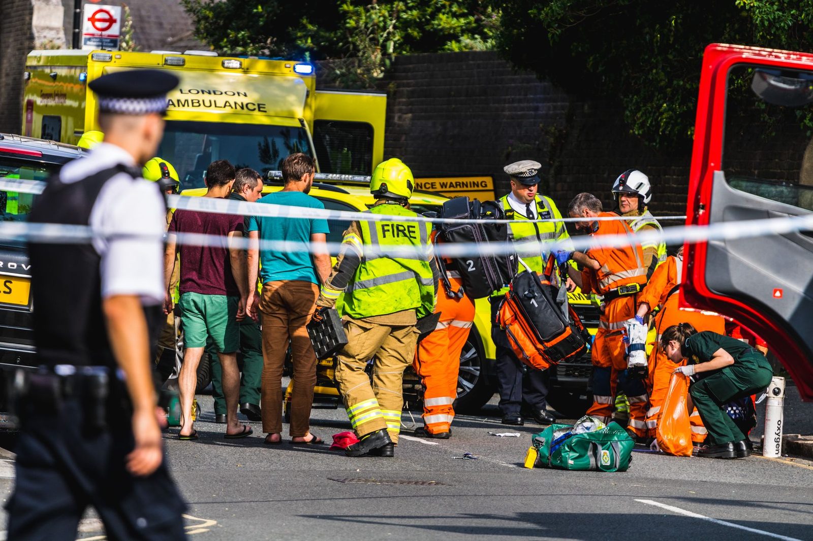Emergency responders attending to a street accident near a London metro station.