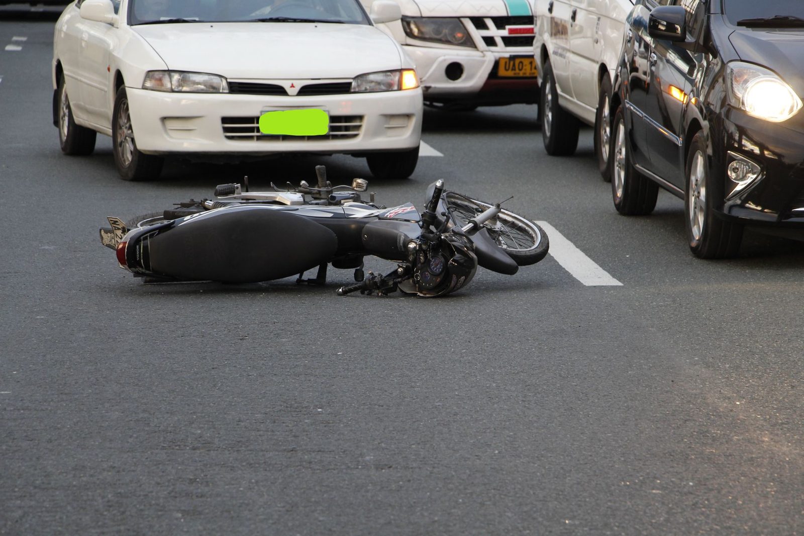 Motorcycle crashed on city road with traffic in background.