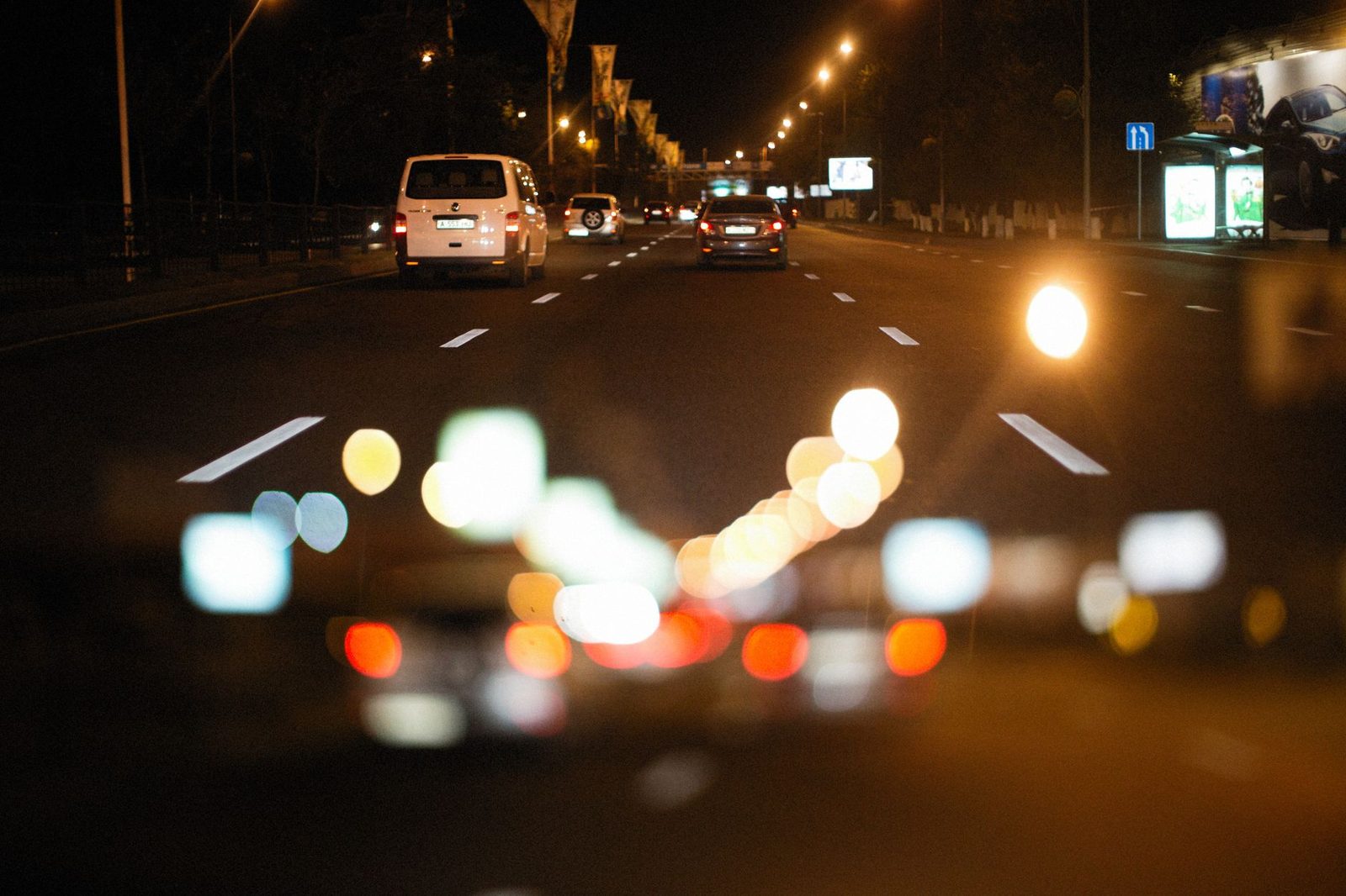 Nighttime city street with blurred bokeh lights and cars in motion.
