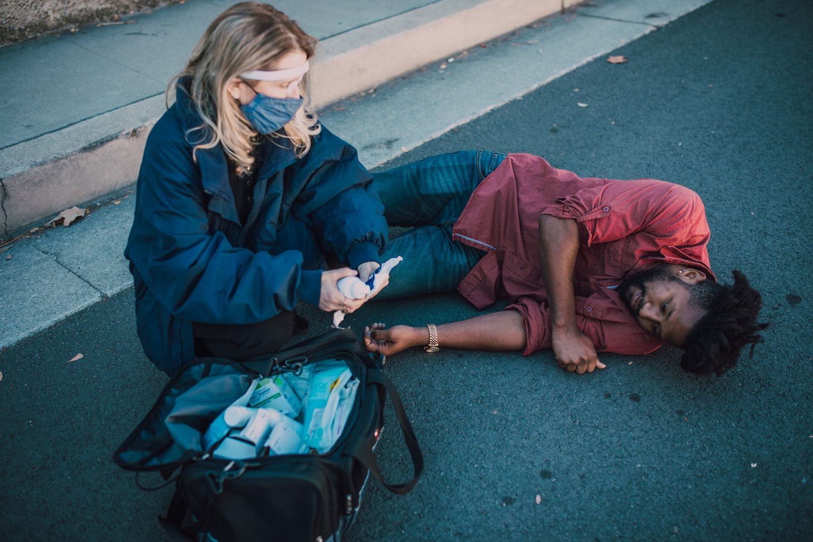 Paramedic administering first aid to an injured person on the roadside.