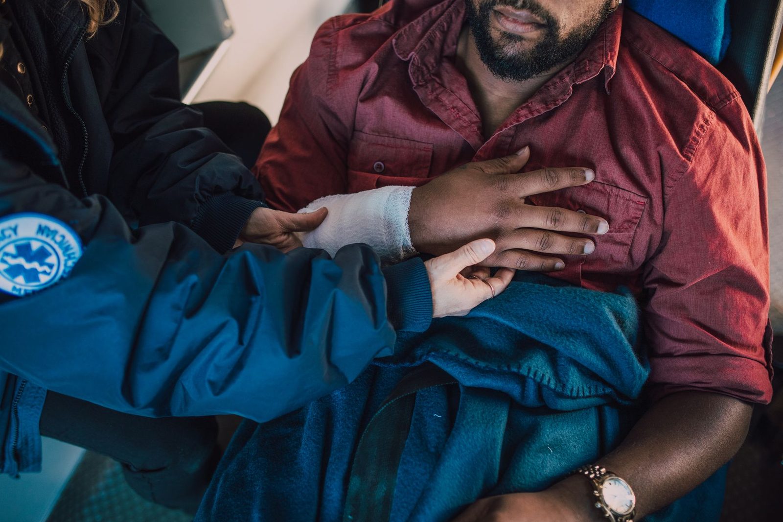 Paramedic bandaging the arm of an injured patient at an emergency scene.