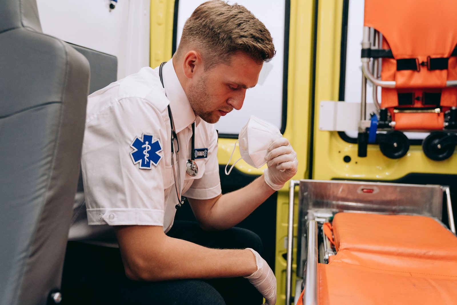 Paramedic in uniform prepares medical equipment inside an ambulance.