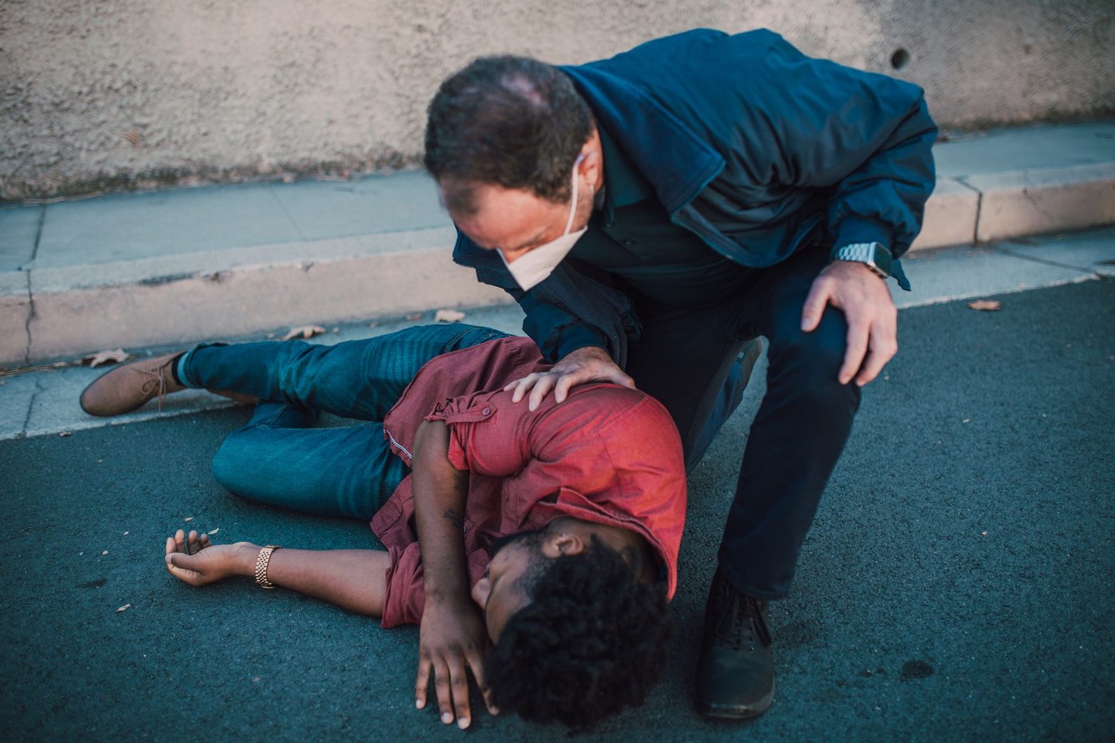 Paramedic providing emergency care to an injured man on the roadside.