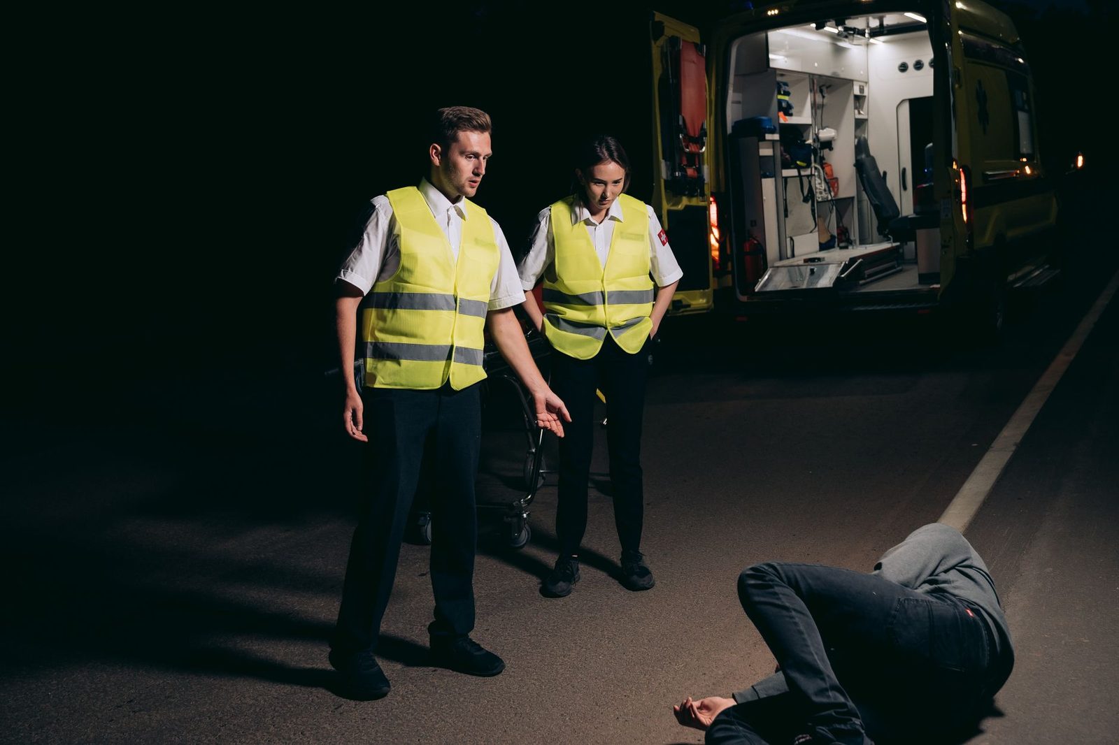 Paramedics providing emergency care to a patient on a nighttime street.