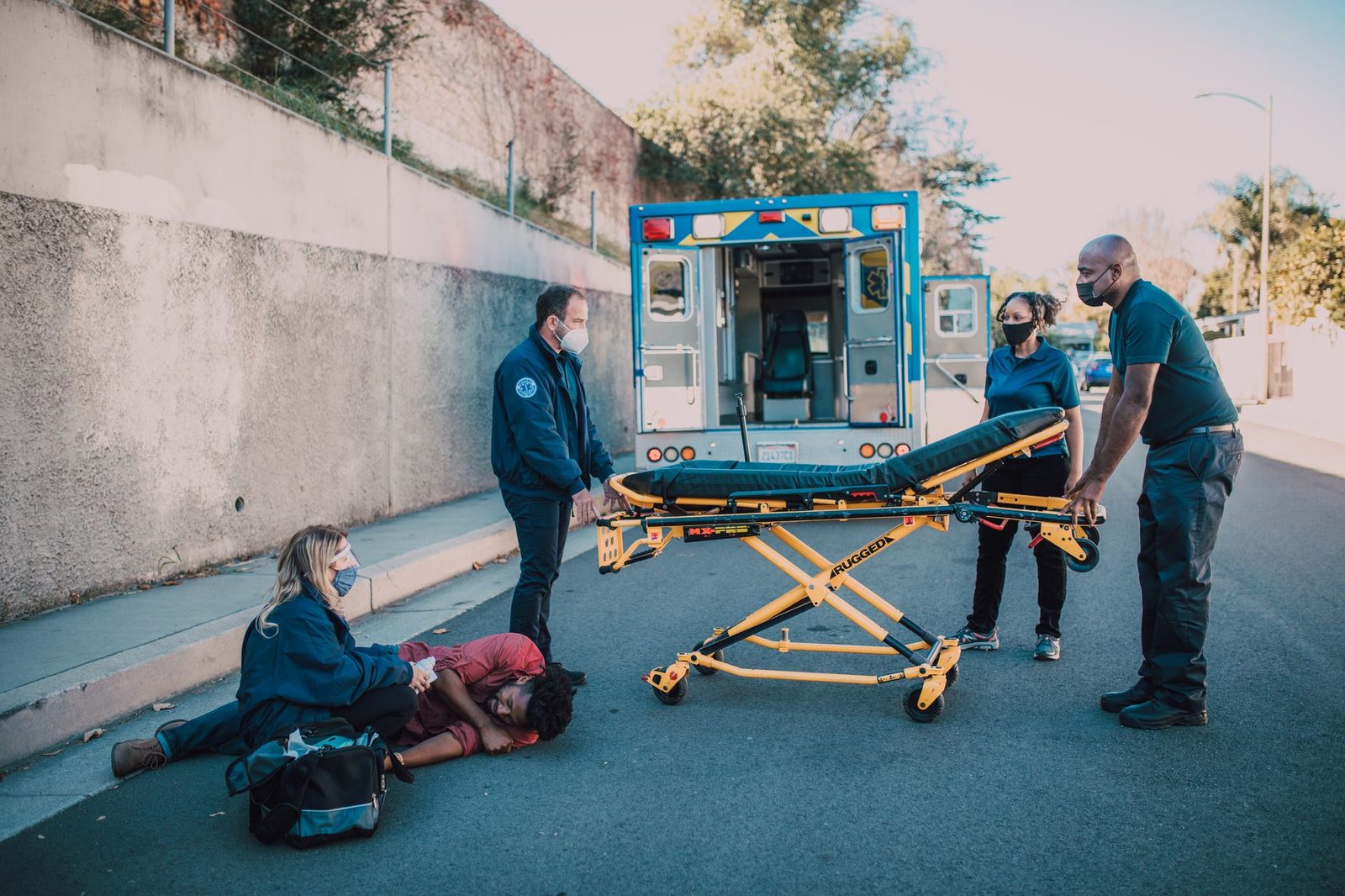 Paramedics providing emergency care to an accident victim on roadside near ambulance.