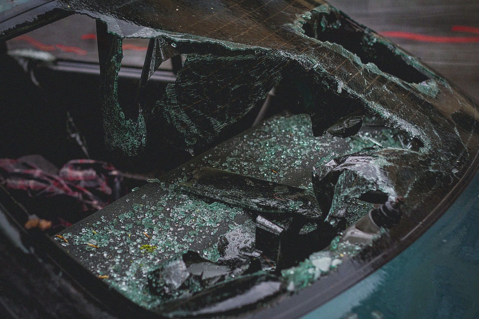 Shattered car windshield with broken glass from vehicle accident.