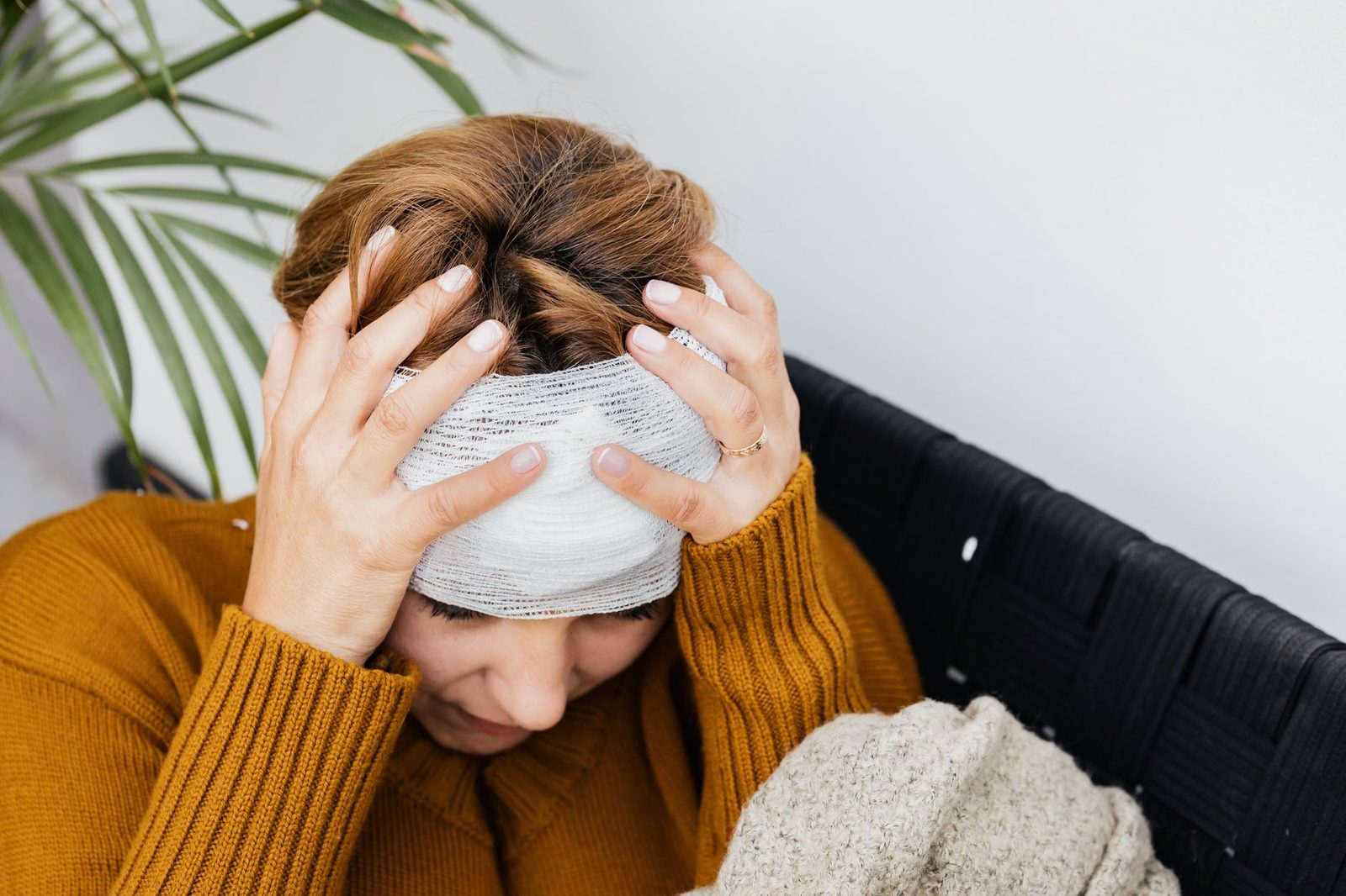 Woman holding her head in pain from injury indoors.