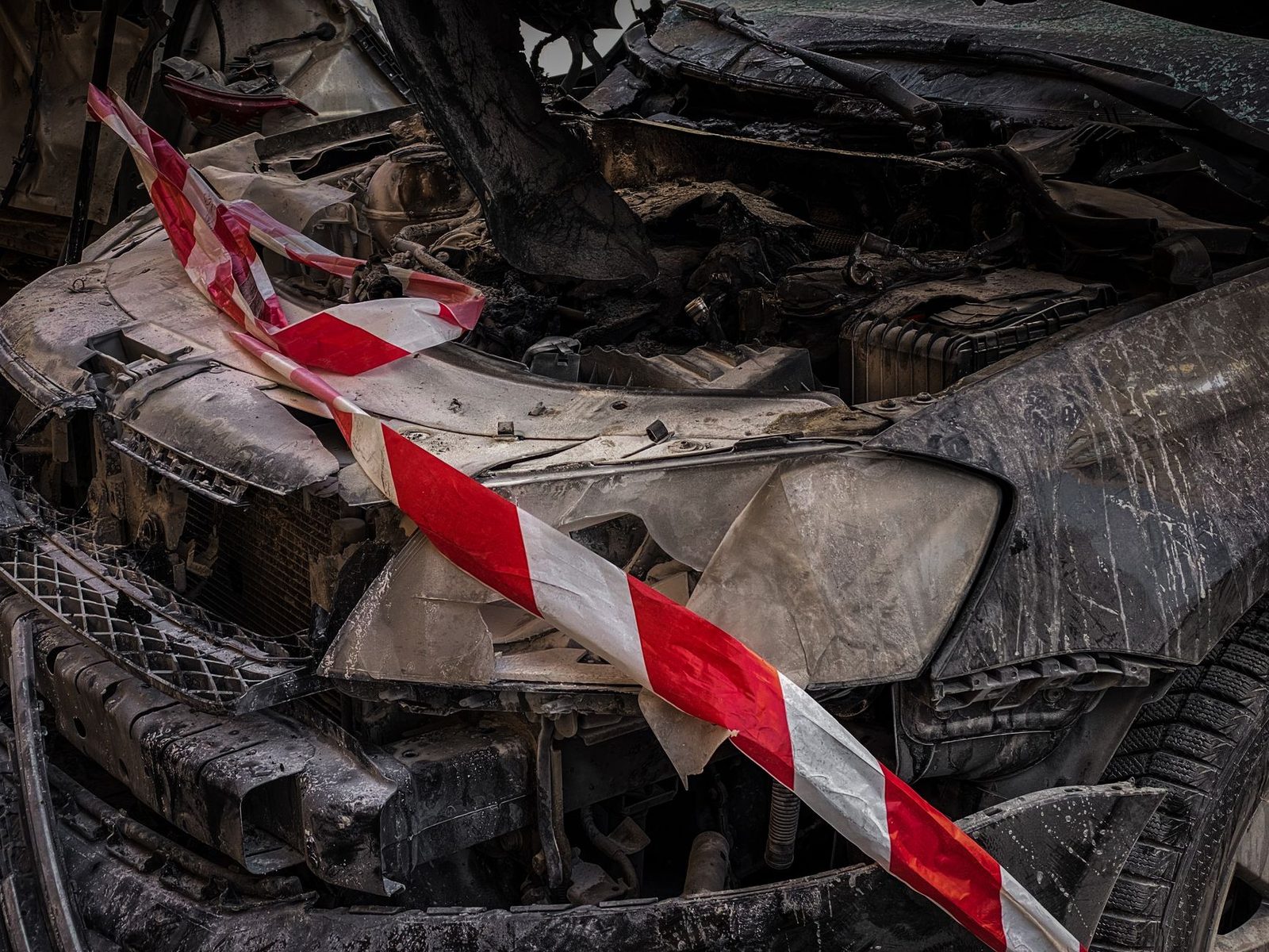 Wrecked car with yellow and black safety tape marking damage.