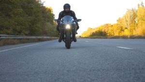 Young man in helmet riding fast on modern sport motorbike at highway. 