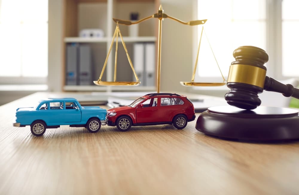 Gavel and little toy car models on desk in courthouse.